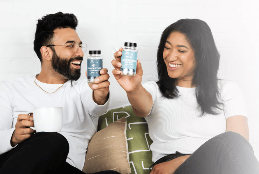 A couple sitting together, each holding their own Eu Natural Conception bottle
